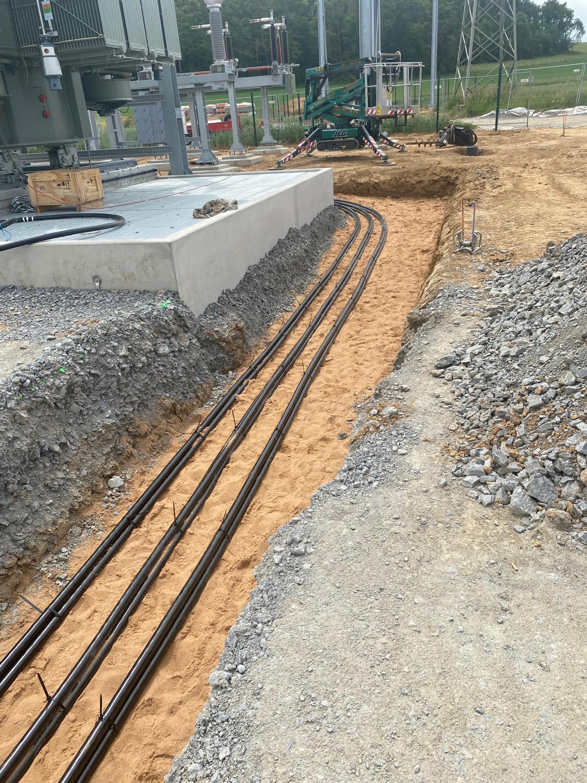 Verlegte Mittelspannungskabel im Sandbett neben Betonfundament