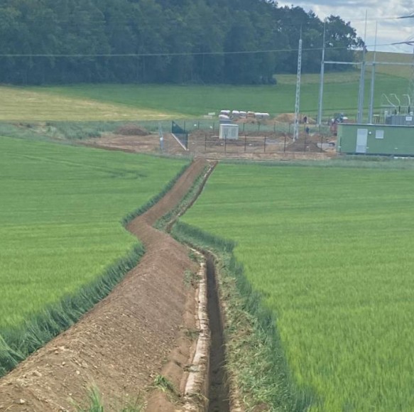 Langer Kabelgraben durch grünes Feld