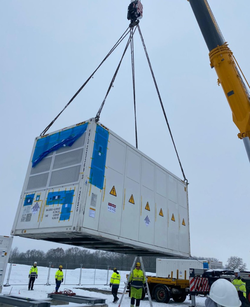 Kran hebt Batteriespeicher-Container auf der Baustelle